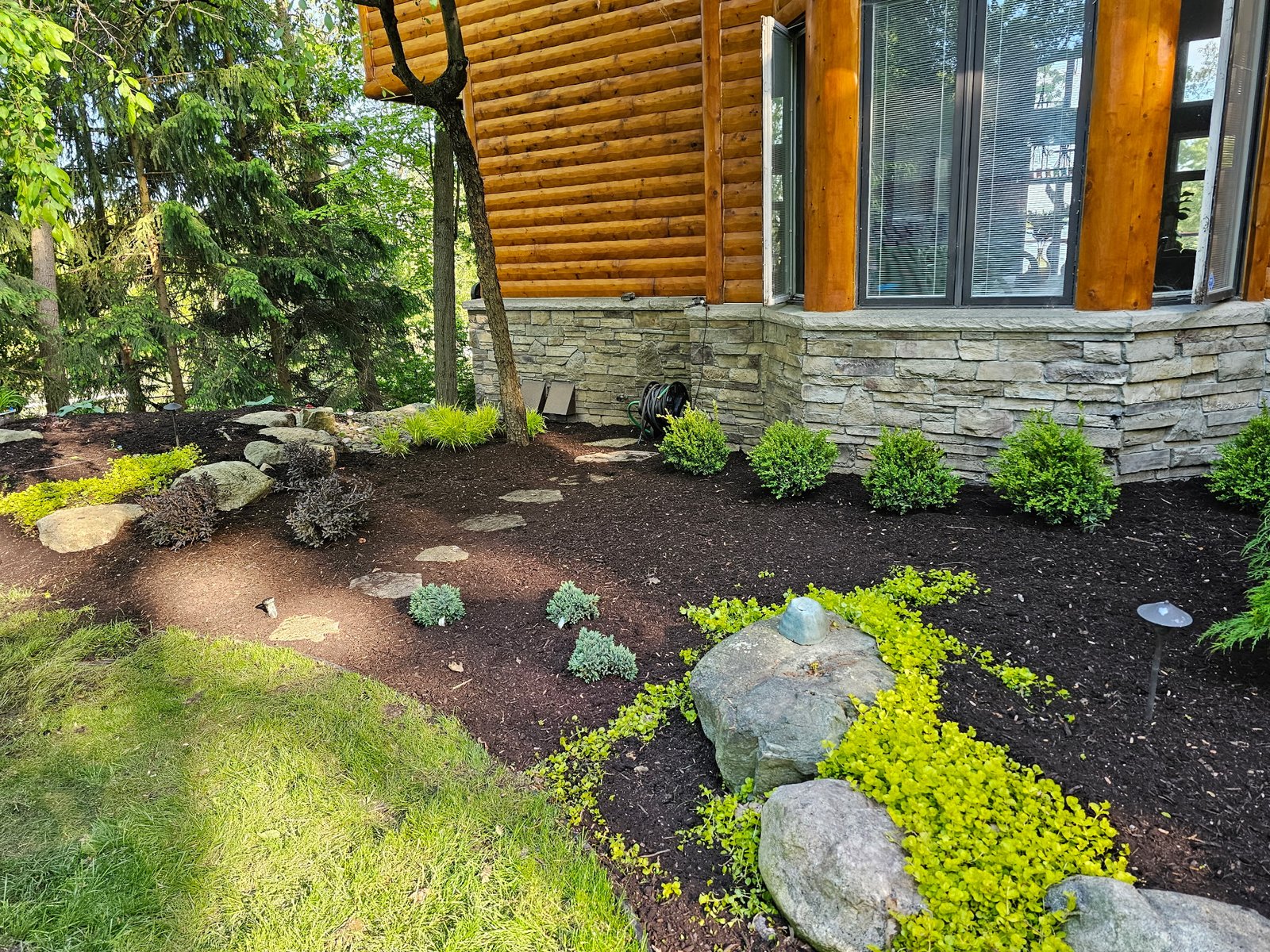 Custom landscape design with stone walkway and garden beds in Washington, MI
